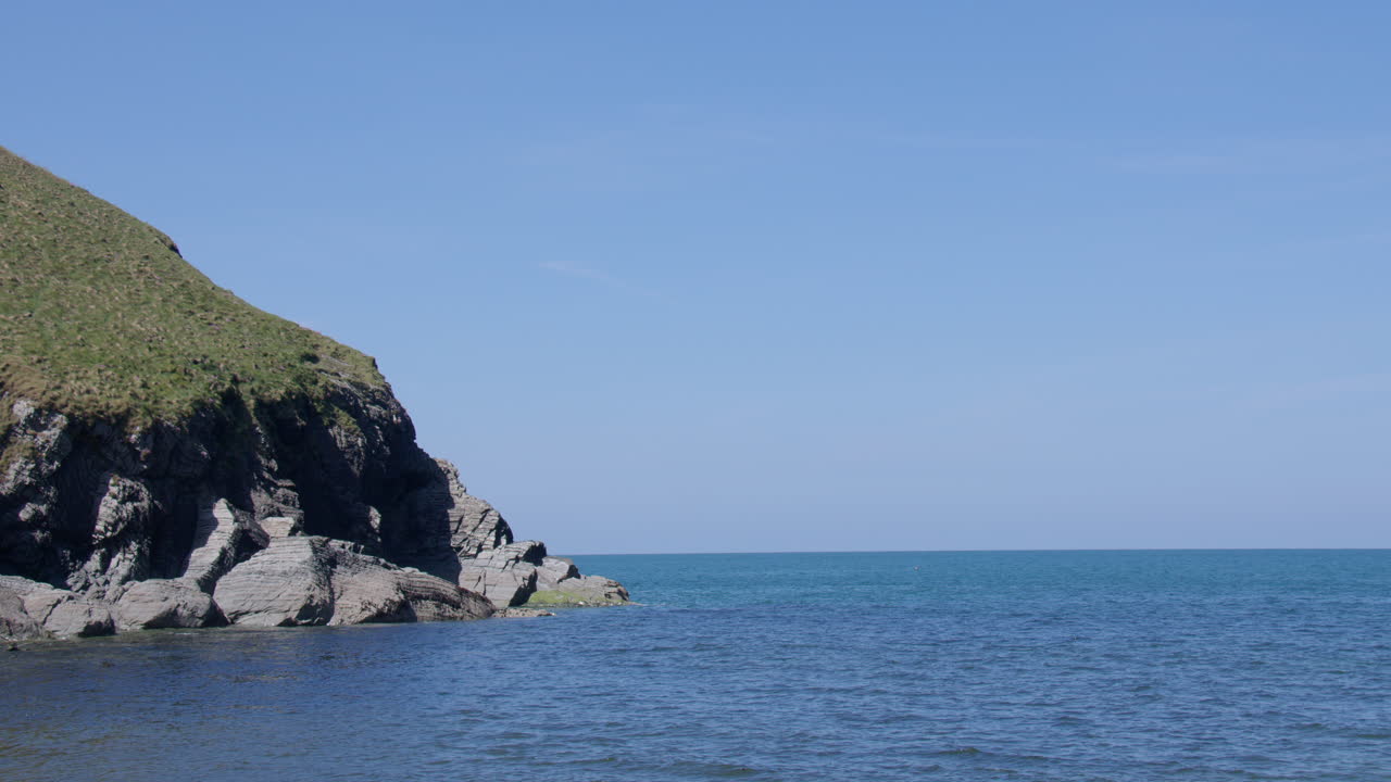 Panning shot of the headland on the West side of Cwmtydu beach