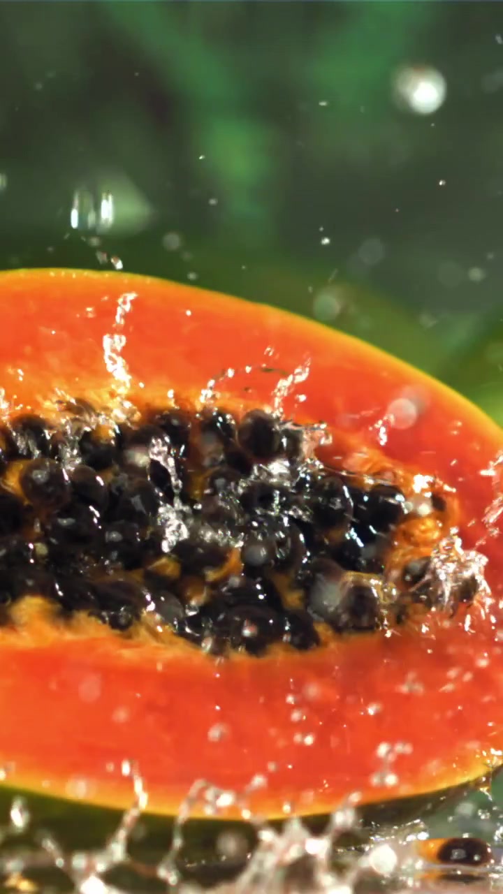 Nærbilde av fersk papaya-halvdel med vannsprut.