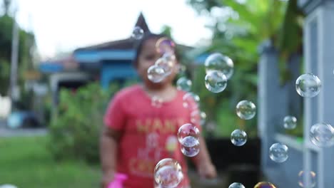 niño asiático feliz jugando con una pistola de burbujas