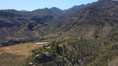 Tamadaba-natural-park,-Tirma:-aerial-view-traveling-out-to-a-fantastic-landscape-with-high-mountains-and-trees-of-this-natural-park-on-the-island-of-Gran-Canaria-on-a-sunny-day