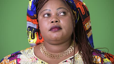 overweight beautiful african woman wearing traditional clothing against green background