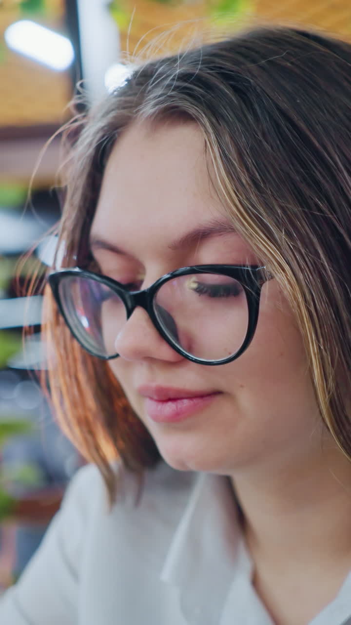primer plano de una mujer joven sentada en un bar, enfocándose atentamente frente a ella con un fondo borroso con luces de colores vibrantes, evocando un estado de ánimo casual y contemplativo