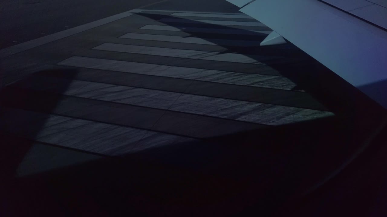 una toma del suelo de una pista, con un ala y su sombra moviéndose sobre ella