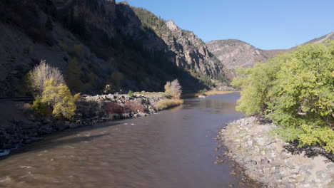 drone view zooming in and following the colorado river forward to the mountains in glenwood springs, colorado