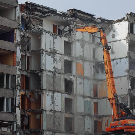 powerful excavator tears off the pieces of destroyed house and throws them down. demolition of a large building ruined by an earthquake