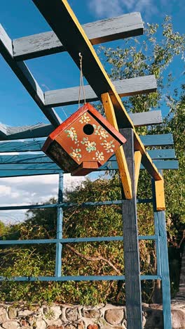 una ornamentada casa de pájaros colgada de una pérgola