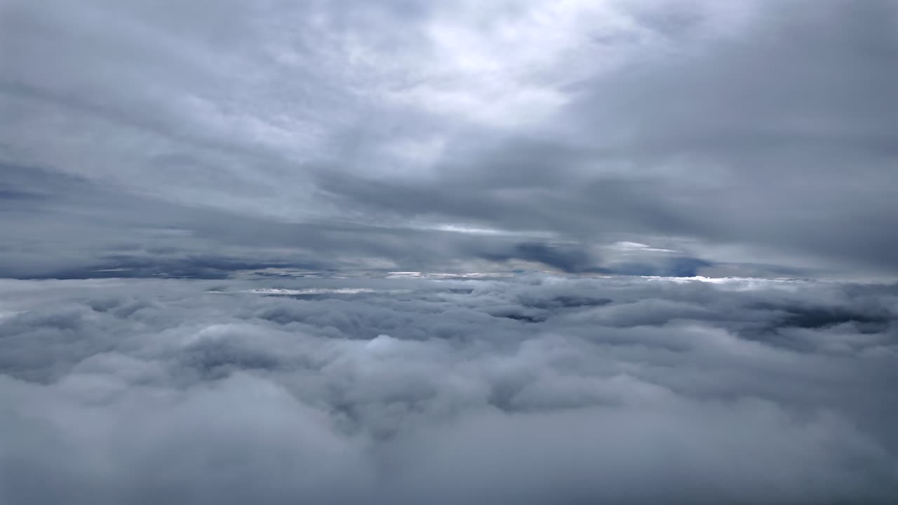 An immersive pilot’s perspective from the cockpit of a jet airplane flying between layers of threatening and darkening stratus clouds in a dramatic sky