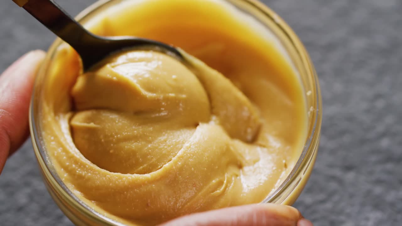 회색 배경에 땅콩 버터와 함께 손의 클로즈업 비디오