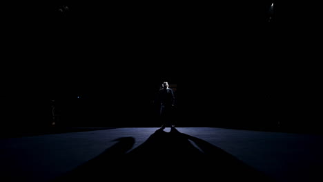 silhouette of a dancer in move. performer dancing on stage against spotlights on dark background. man acting in the theater.