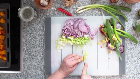 Hand-Cutting-Ginger-Into-Small-Pieces-Next-To-Chopped-Onions