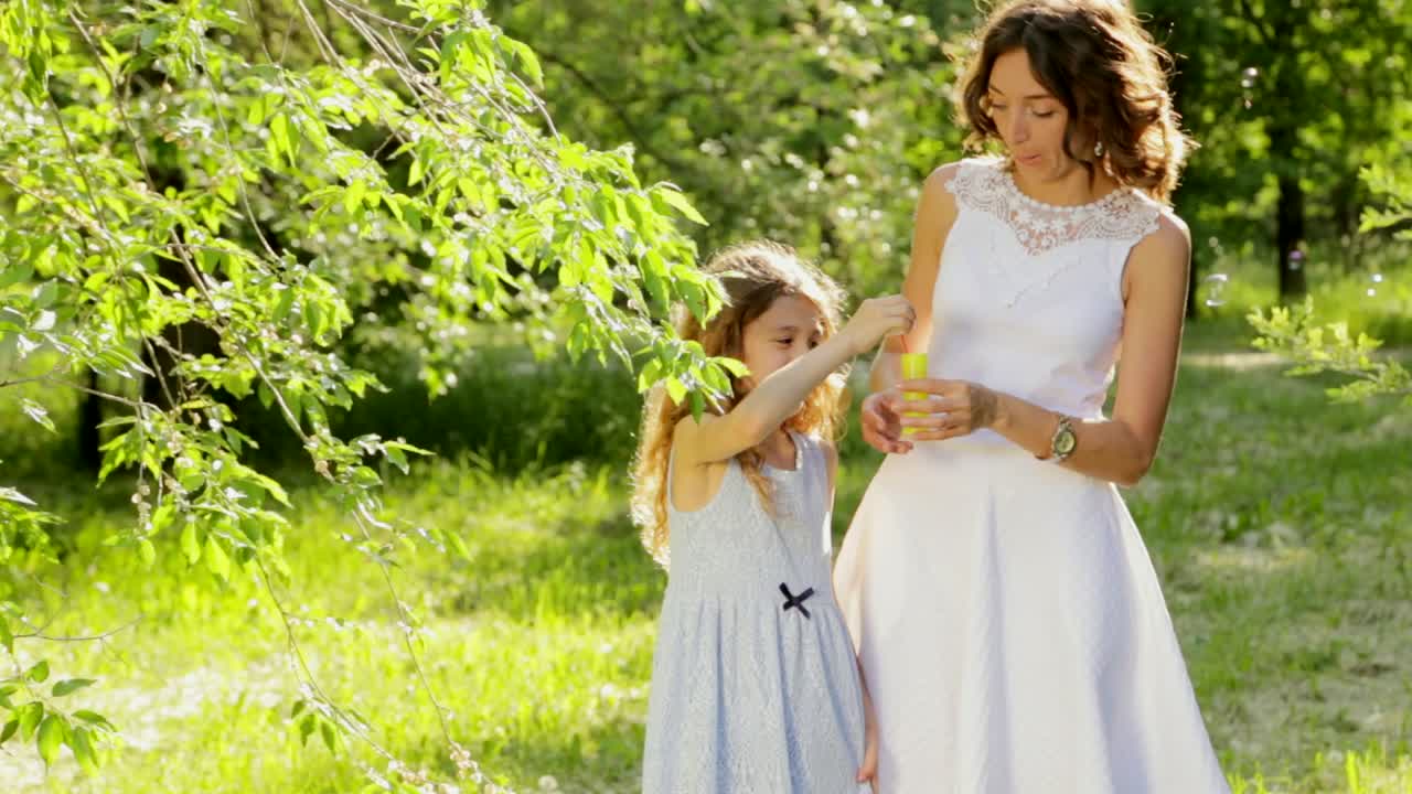 madre e hija jugando con burbujas en un parque