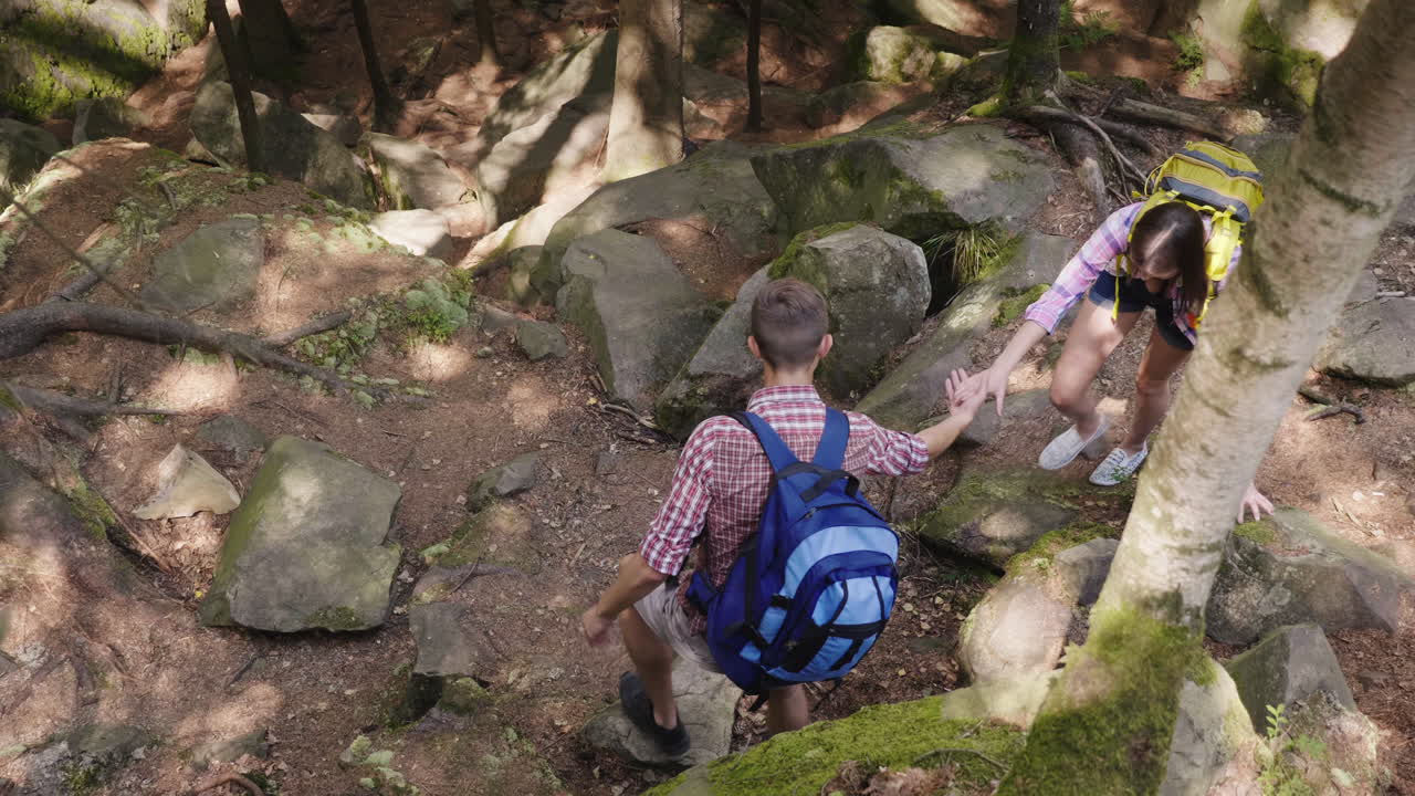un hombre ayuda a una mujer a subir un sendero empinado caminando por el bosque caminando y un estilo de vida activo