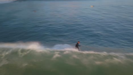 aerial-view-of-a-skilled-surfer-generates-incredible-speed-as-they-expertly-maneuver-through-the-waves,-effortlessly-trimming-and-gliding-with-impressive-speed-in-estoril-beach,-cascais