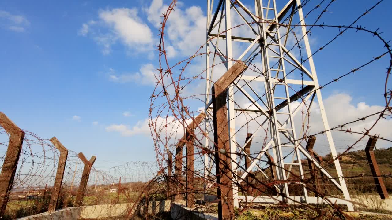 cerca de alambre de púas que rodea una torre de vigilancia, lapso de tiempo se inclina hacia arriba desde el suelo hasta el cielo