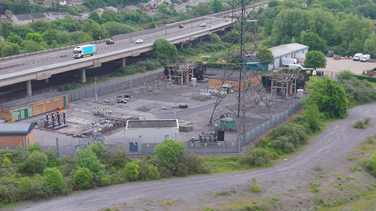 Hoogspanningsstation met nabijgelegen M4 snelweg. Kritieke infrastructuur van een modern elektriciteitsnet, energiedistributie, industriële engineering. Wales, VK. 4K
