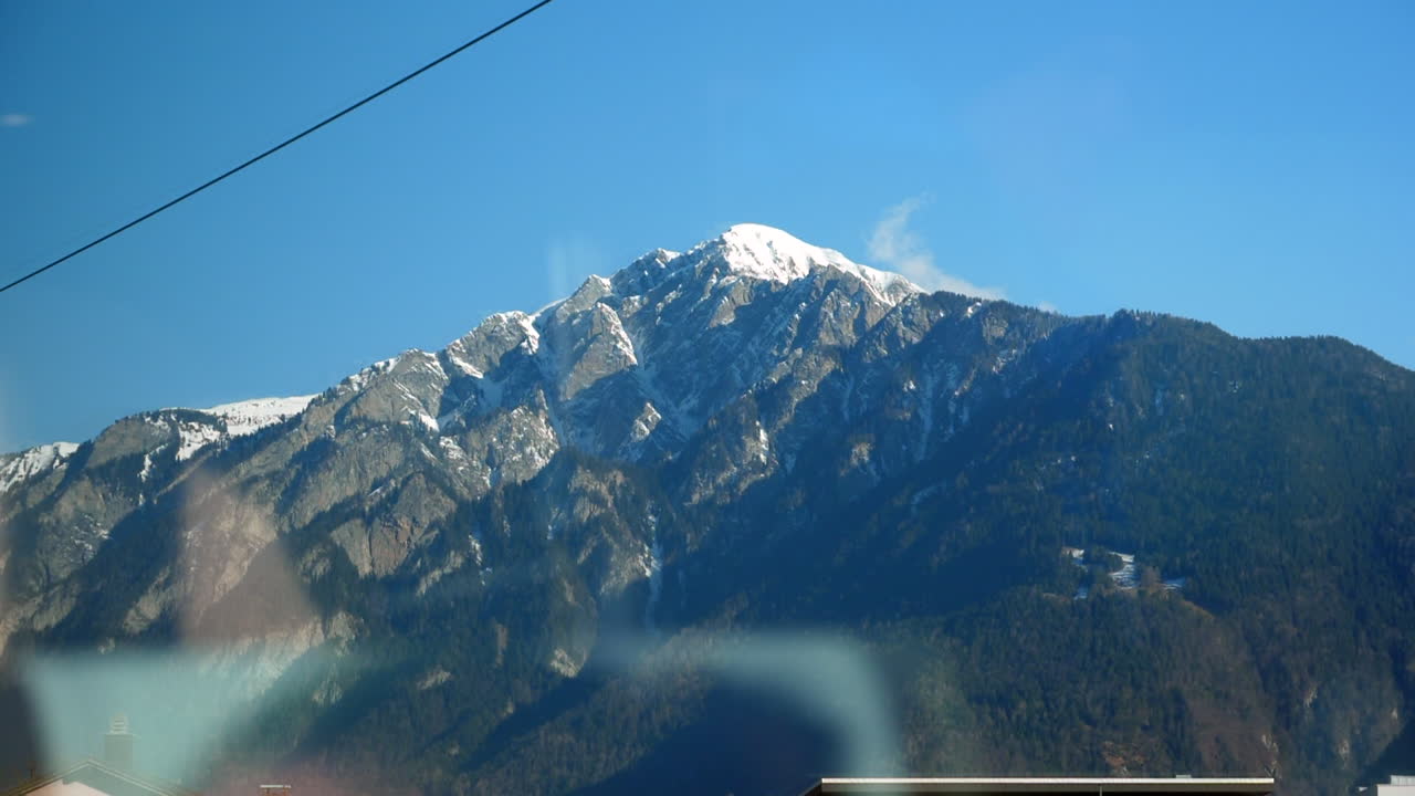 vista del viaje en tren expreso glaciar con reflejo de ventana y mezcla de viviendas rurales y montañas