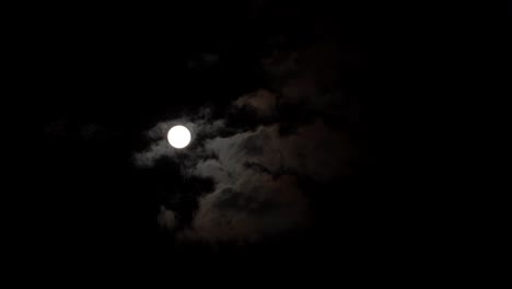 moon glowing through clouds on dark night black sky timelapse