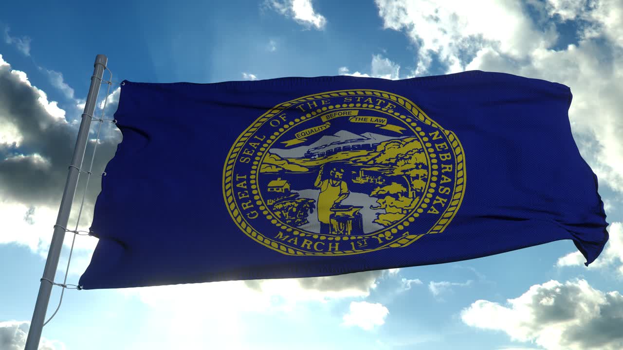 la bandera de nebraska en un asta de bandera ondeando en el viento, fondo de cielo azul. 4k
