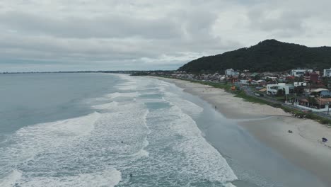 Luftaufnahme-Eines-Dollys-In-Richtung-Küstenstrand,-Bewachsener-Berg-Im-Hintergrund