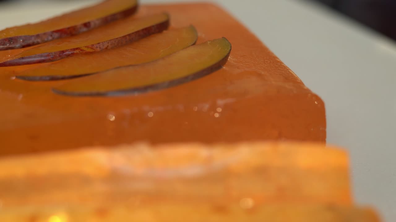 Close up of Turkish delight rotate on tray on background of ripe plums. Fruit dessert, marmalade, jujube.