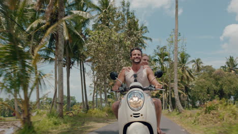 travel couple riding scooter on tropical island happy woman celebrating with arms raised enjoying fun vacation road trip with boyfriend on motorcycle ride