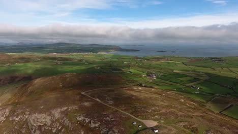 aerial view travelling overland on the tip of the llyn peninsula from the headland at mynydd mawr towards the bay of aberdaron with dramatic cloudy blue sky