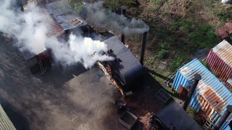 aerial view of unrecognizable woodsmen loading a retort in charcoal production