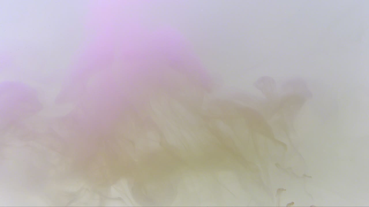 Colorful paint drops mixing in water. Smooth ink swirling and splashing from above underwater. Ink cloud isolated on black background. Colored abstract smoke explosion