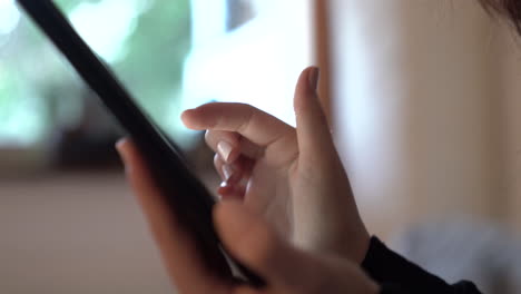 Close-side-view-shot-of-a-woman's-hands-using-a-tablet,-scrolling-on-touch-screen