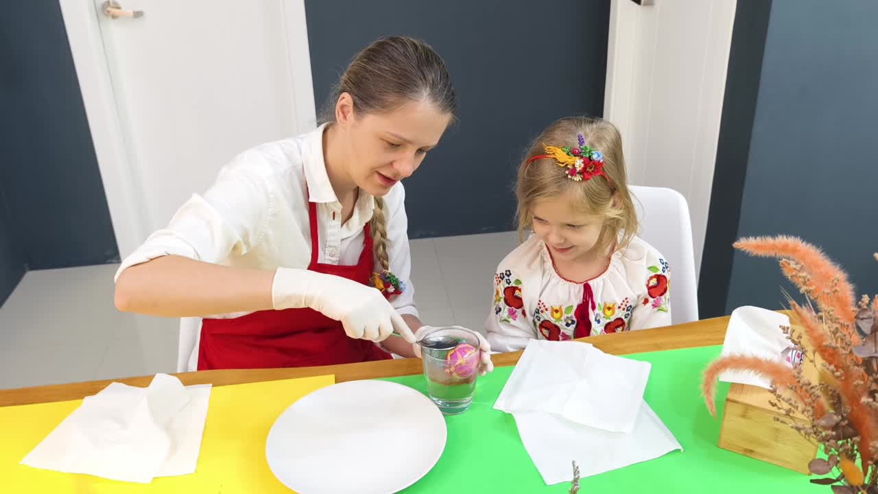 мать и дочь украшают пасхальные яйца.