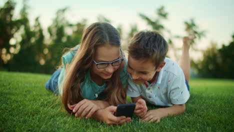 Junge-Und-Mädchen-Liegen-Mit-Mobiltelefon-Im-Gras.-Bruder-Und-Schwester-Nutzen-Smartphone