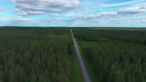 Lone-car-driving-along-straight-long-tarmac-forest-road