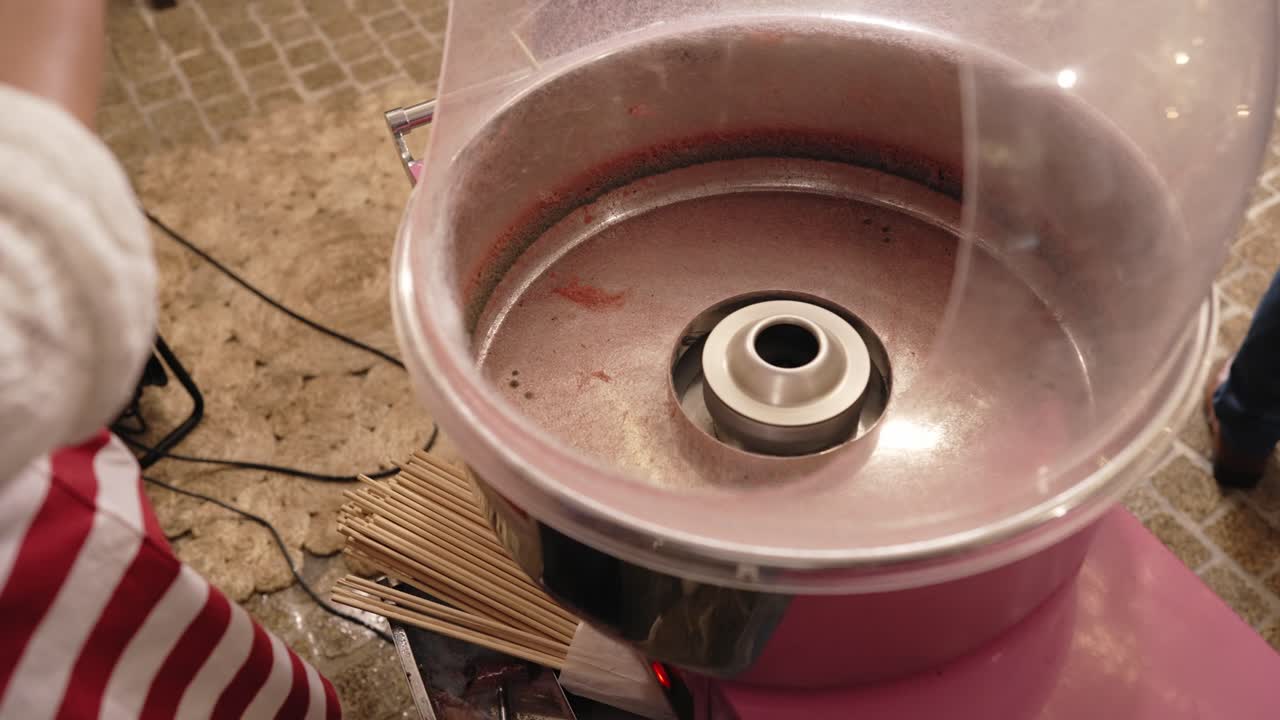 Close up of white cotton candy being lifted from machine in festive setting indoors