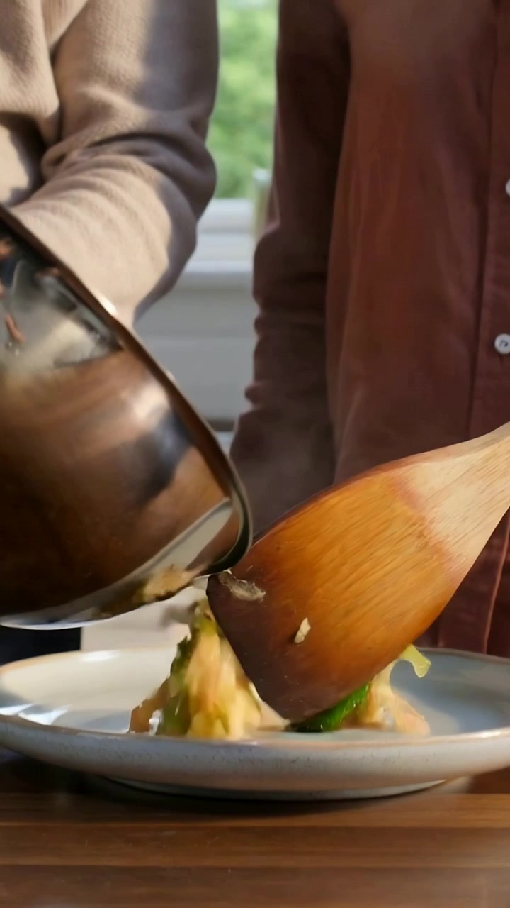 Vertical video: Tilting bowl couple in sweater plating eggs with wooden spatula onto plate at home