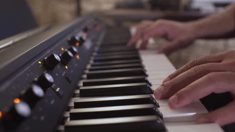 caucasian male plays synthesizer in home studio