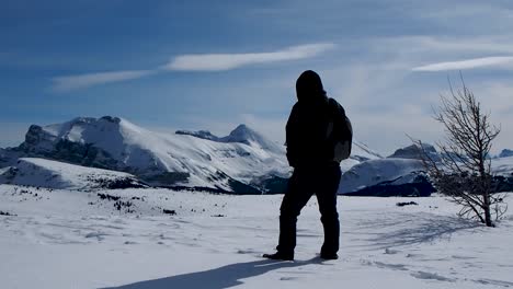 Man-walking-in-snow-on-top-of-mountain