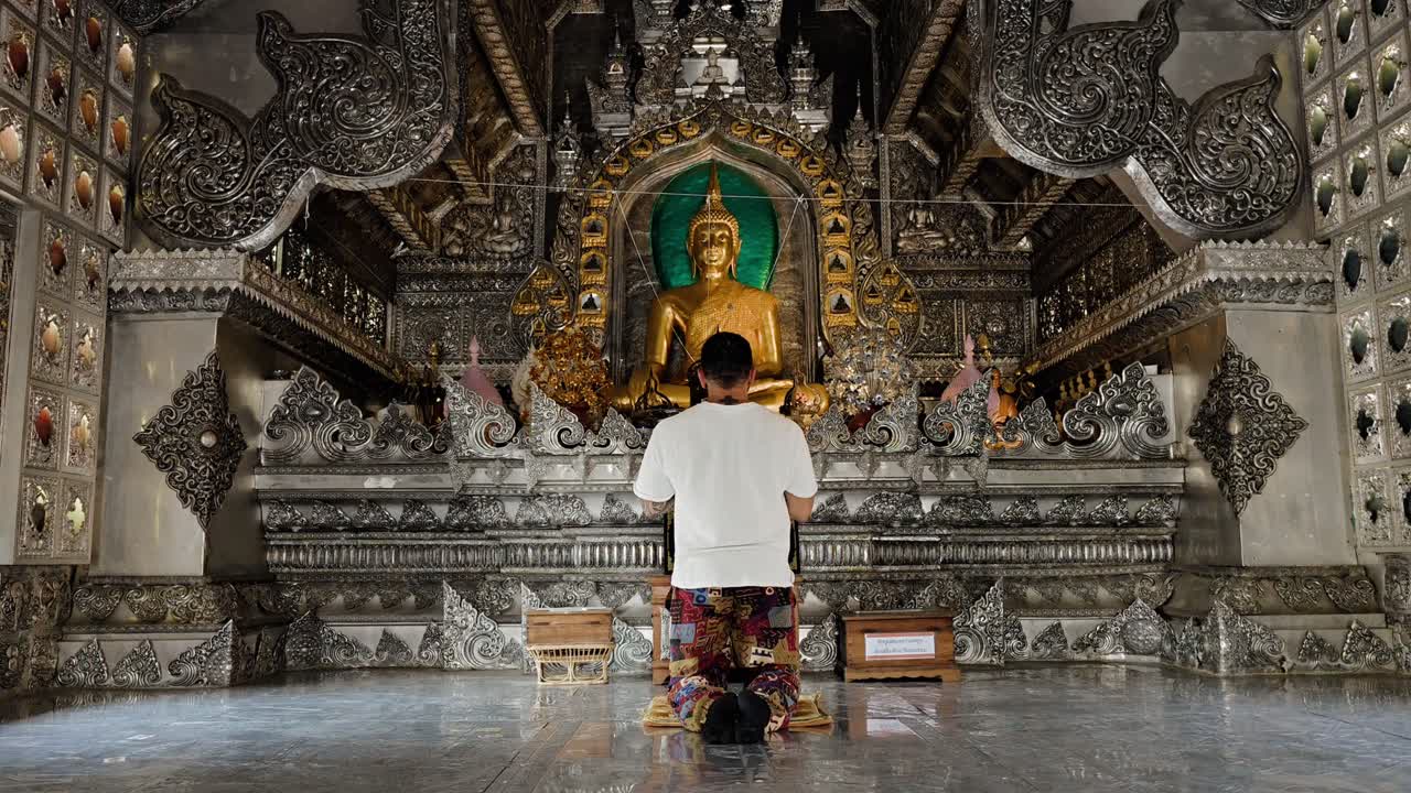 man praying at the silver temple in chiang mai