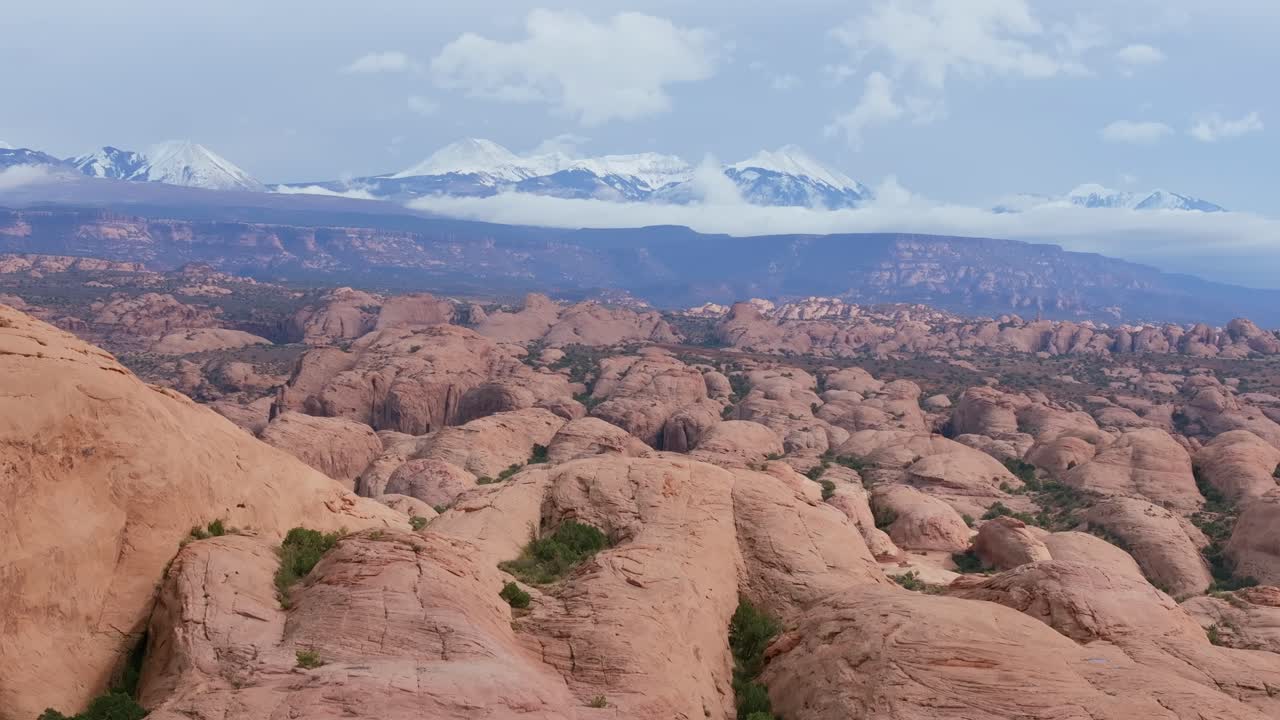 Aerial view rising over red rock crest to reveal Moab Utah desert landscape