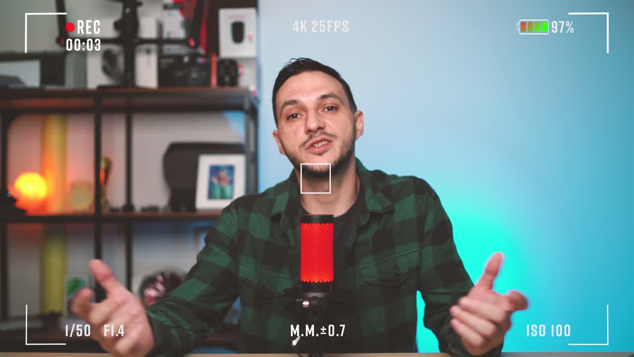 Professional man recording podcast while speaking into microphone in front of camera with live recording overlay. Modern content creator setup with studio lights, headphones, and computer screen