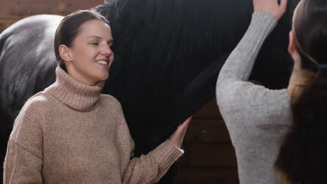 two girls talking while they pet a horse