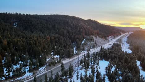 an aerial pan of cars driving on cariboo highway 97 during a winter sunrise in british columbia, canada