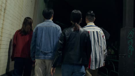 group of people walking at night through an urban tunnel