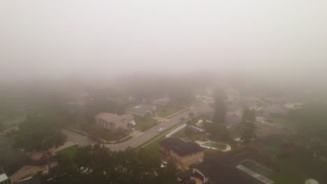 aerial reverse flyover through foggy and misty neighborhood in city of ocoee, florida with no vehicles driving