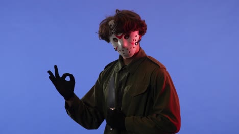 man in white mask with big sharp knife on blue background with red neon light image of jason