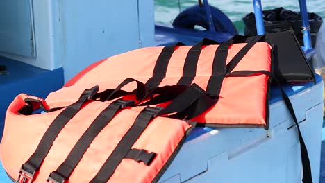 a person places a life jacket on a boat seat under bright daylight in phuket, thailand, emphasizing safety and preparedness