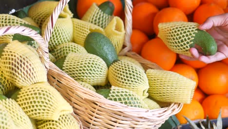 aguacates y naranjas en una canasta en una tienda de comestibles