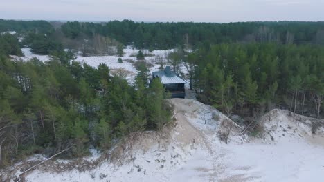 aerial establishing view of baltic sea coast on a overcast winter day, a tiny gray holiday house at the beach with white sand, coastal erosion, climate changes, wide slow orbiting drone shot