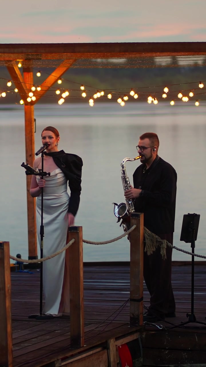 Musikduo optræder live på en sømole ved solnedgang