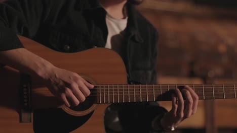 a handsome guy plays an acoustic guitar in an abandoned cinema. the musician sings a song and accompanies on the guitar