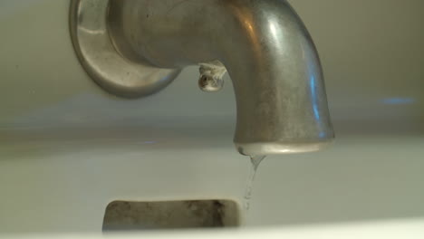 Slow-motion-medium-shot-of-a-faucet-as-the-water-shuts-off-and-drips-of-water-continue-to-fall